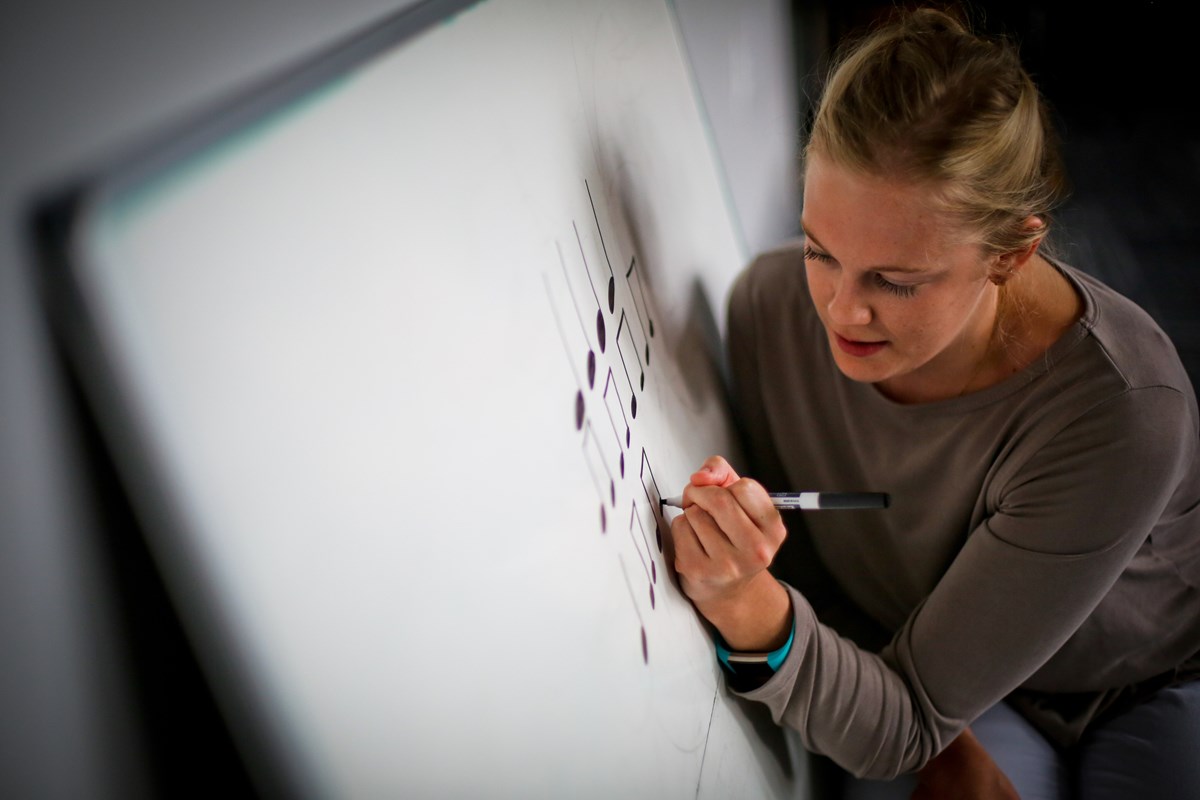 A female teacher reviews notation on a white board in a Kindermusik Musicians class, an ideal precursor to music lessons for kids.