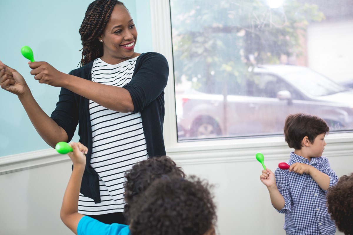 Teacher shakes maracas with preschool students while using Kindermusik’s music programs for schools.