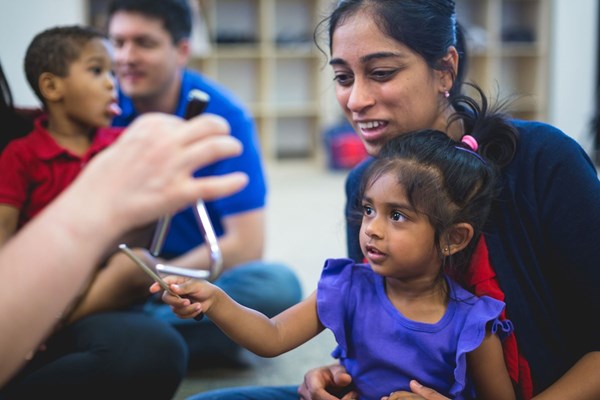 Mother and son play triangle together during music classes for early Pre-K.