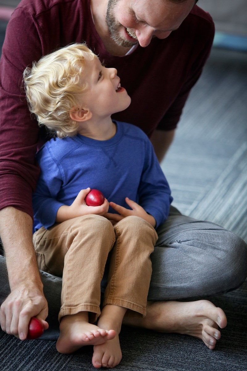 Preschooler sitting and exploring sticks. What to expect in a music class for preschoolers.