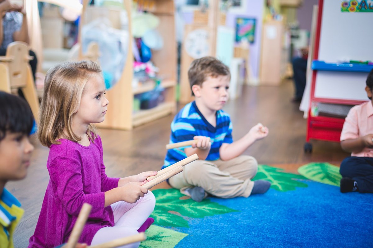 Children grasping rhythm sticks. Kindermusik aligns with various music program alignments.