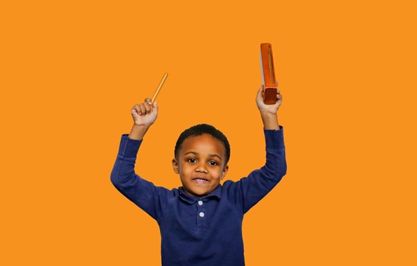 Preschool-age boy tapping a resonator bar. About Kindermusik classes for families and caregivers.