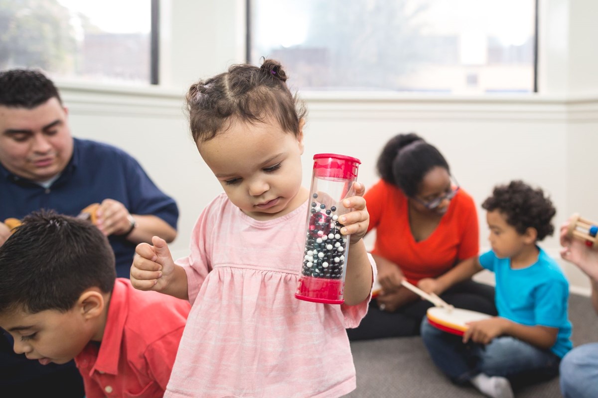 Two year old exploring rain shaker. What to expect in a music class for two year olds.