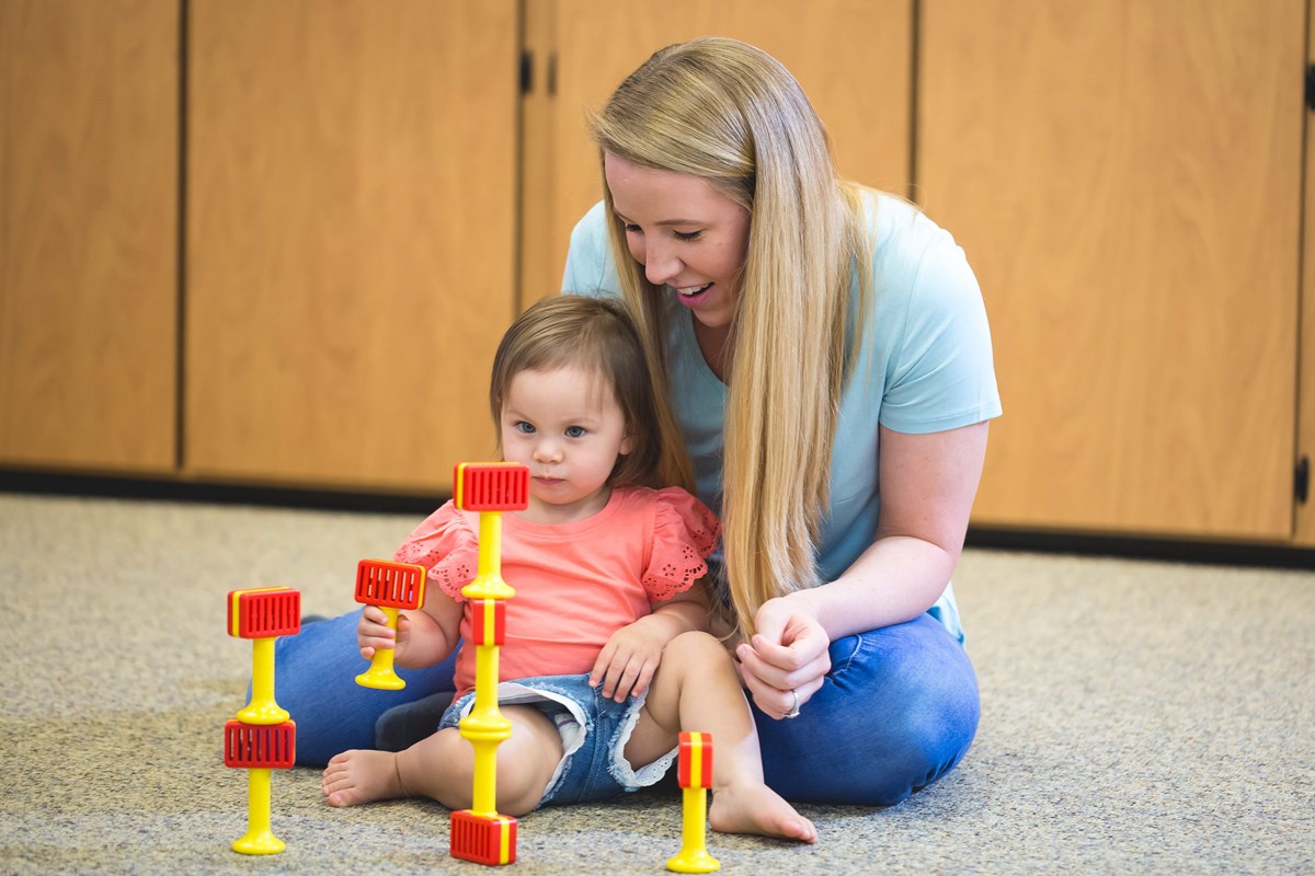 Adult and child stacking cage bells. Music and movement research on how Kindermusik affects mathematics achievement.