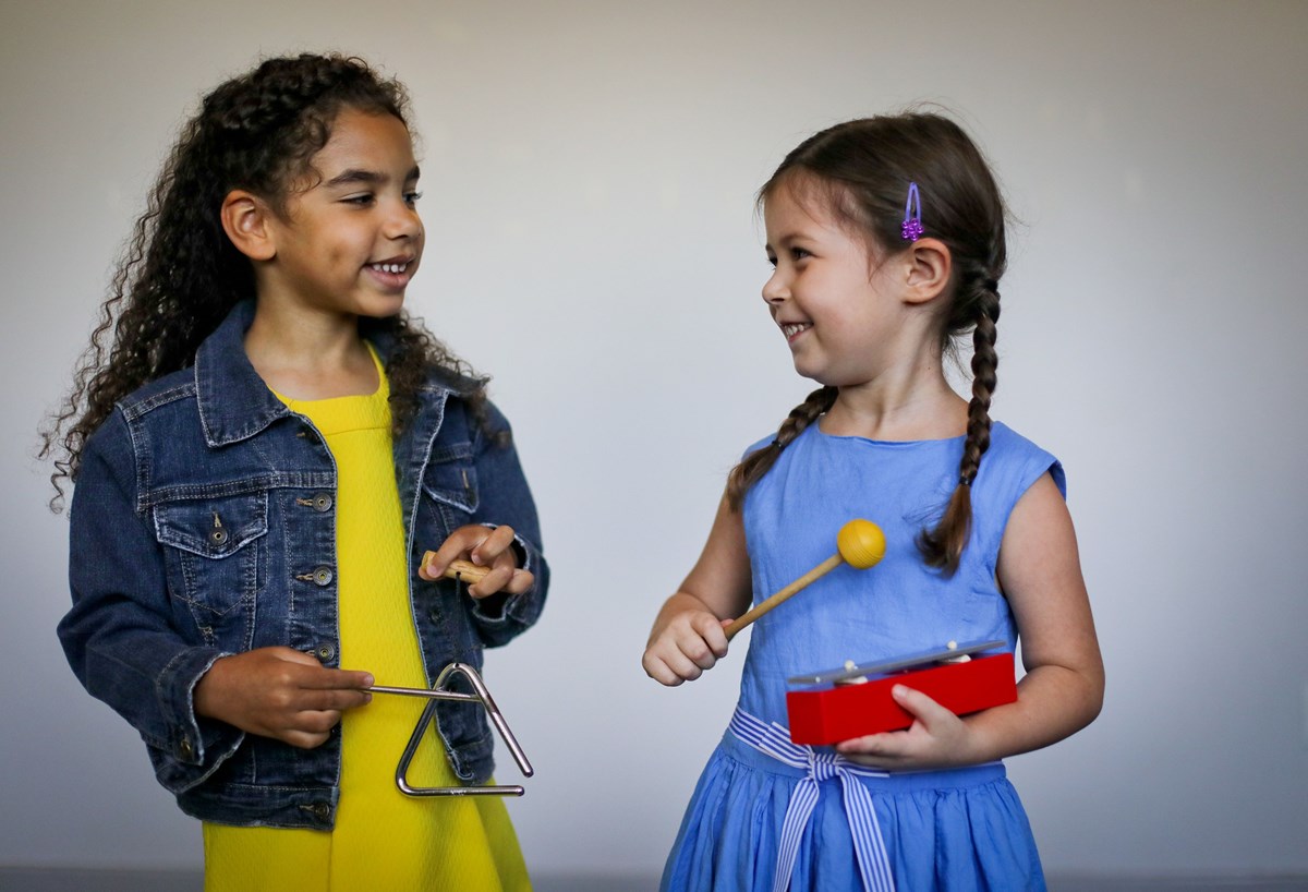 Young girls playing triangle and resonator bar. What you’ll learn in music lessons for beginners.